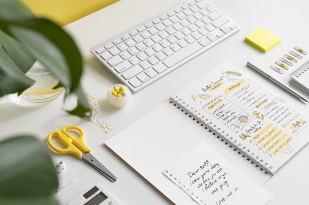 An aesthetic white desk with planner and written ideas and a keyboard