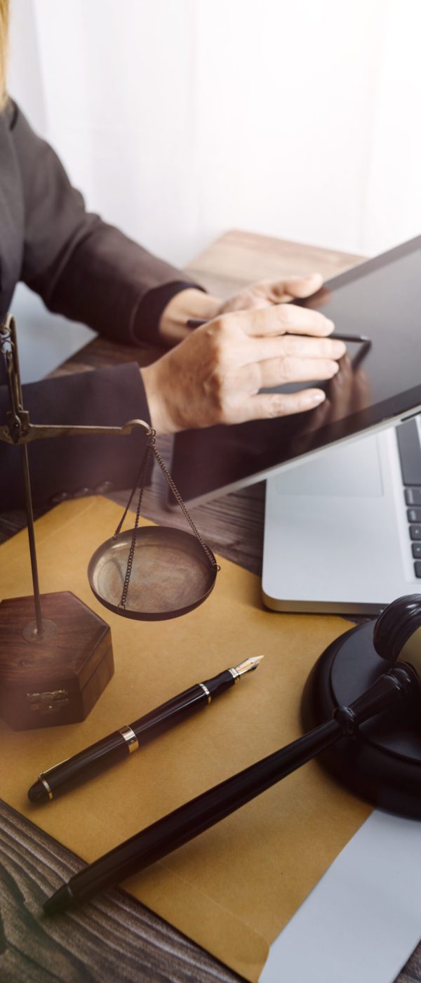 Prawniczka korzystająca z tabletu i laptopa, obok wagi i młotka sędziowskiego - nowoczesny marketing prawniczy w codziennej pracy